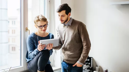 Ein Mann und eine Frau schauen sich über ein Tablet eine Website an.